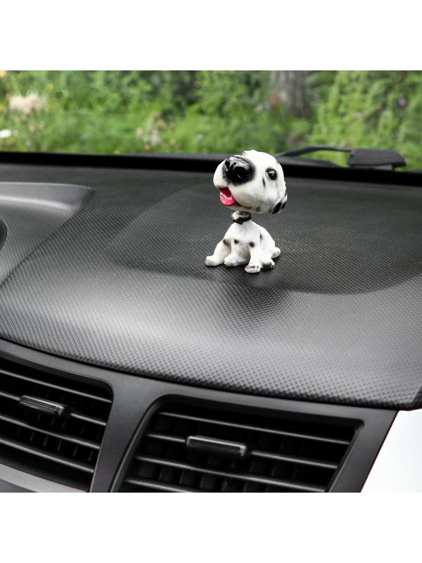 Собака на панель авто, качающая головой, далматин